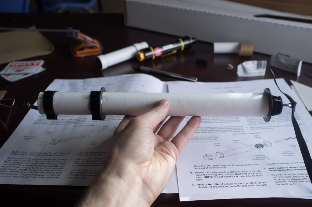 One motor mount ready to go. Not seen: the cool internal steel-ribbon baffling designed to cool the gasses from the ejection charge before they reach the fragile lightweight parachute. Rocket science, folks. 